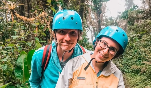 Sarah and her significant other before zip lining in Costa Rica wearing their blue helmets
