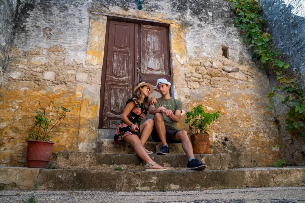 Mansoureh and significant other in front of a brown door and a stone structure in Rhodes