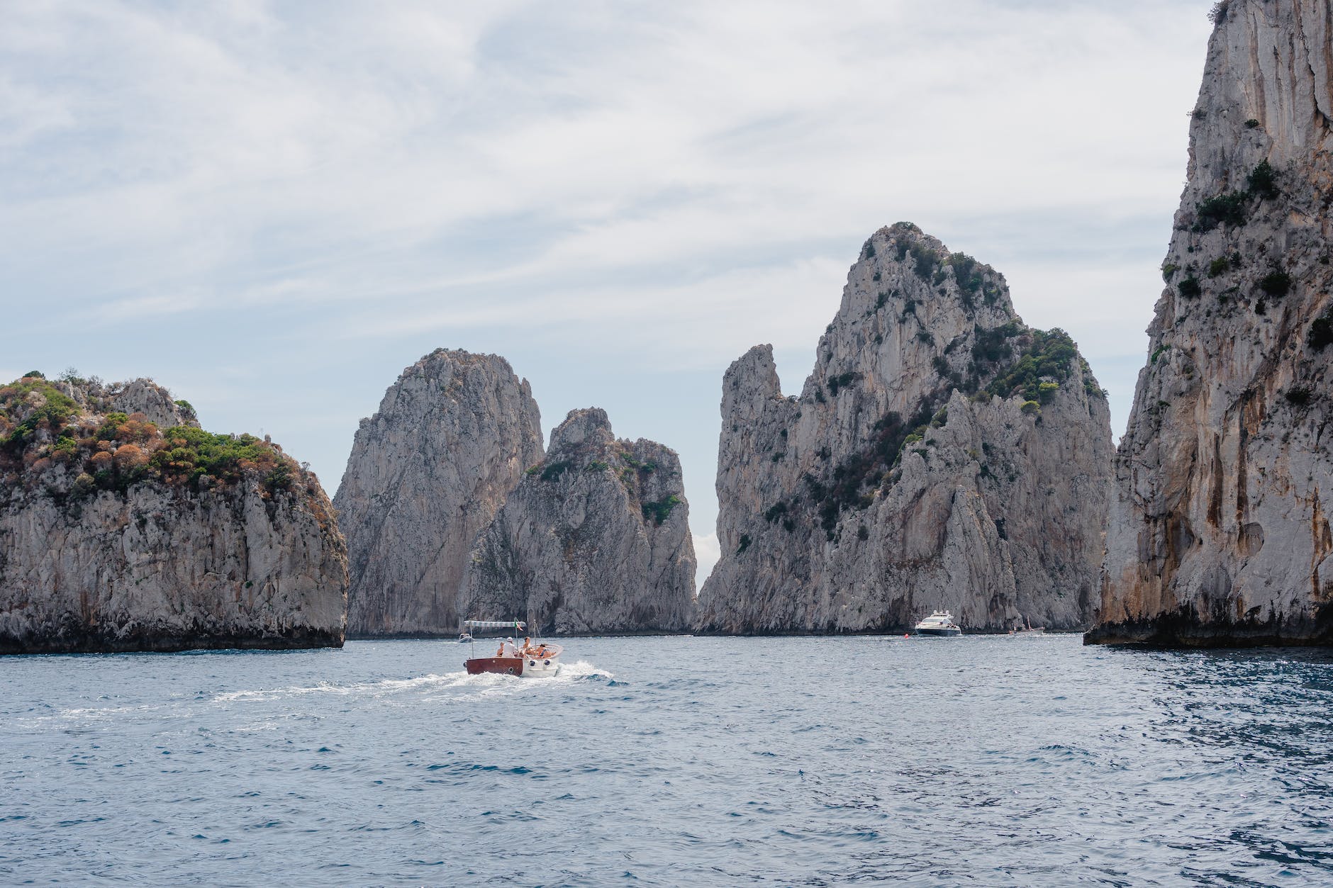 boat sailing at sea surrounded with gray mountains in Capri