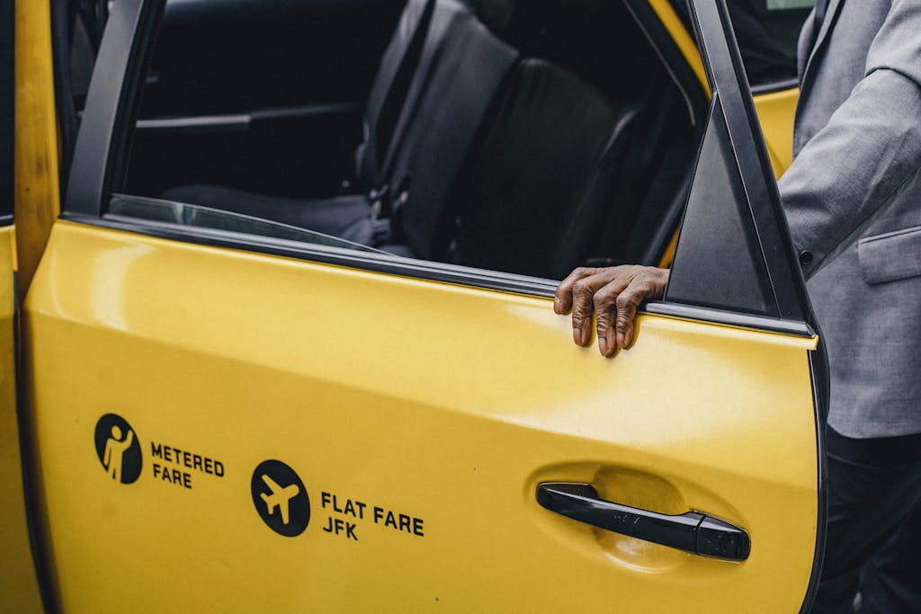 How to Choose Reliable Airport Cabs in 2025 1 A person opens a yellow taxi door with JFK flat fare signage.