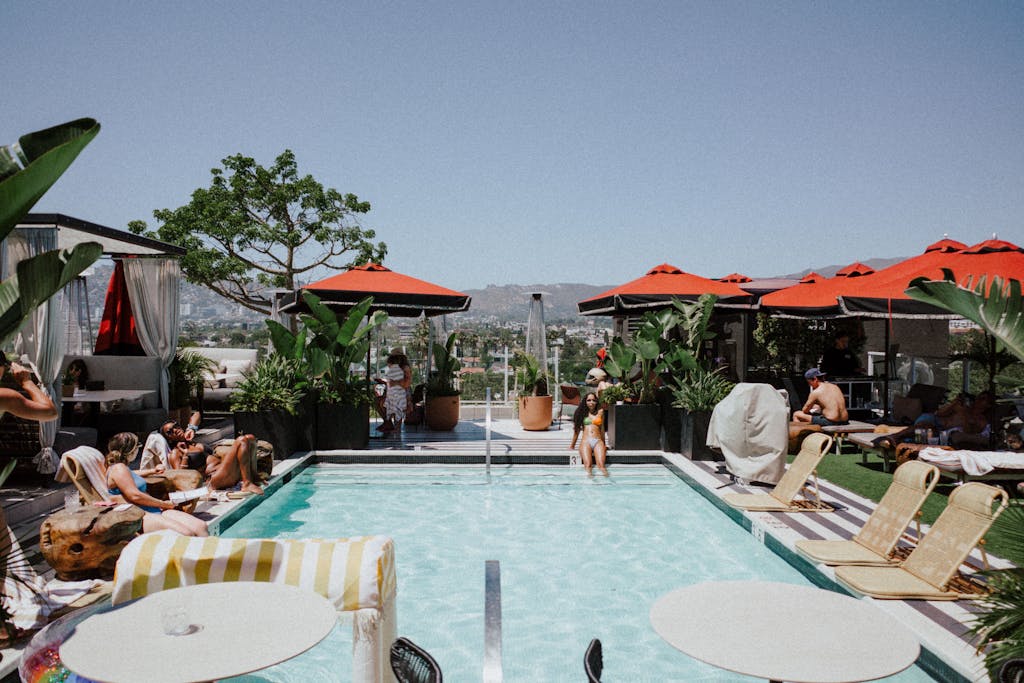 Donde Alojarse en Los Angeles en 2026 11 Rooftop pool scene with people relaxing, surrounded by umbrellas in West Hollywood, CA.