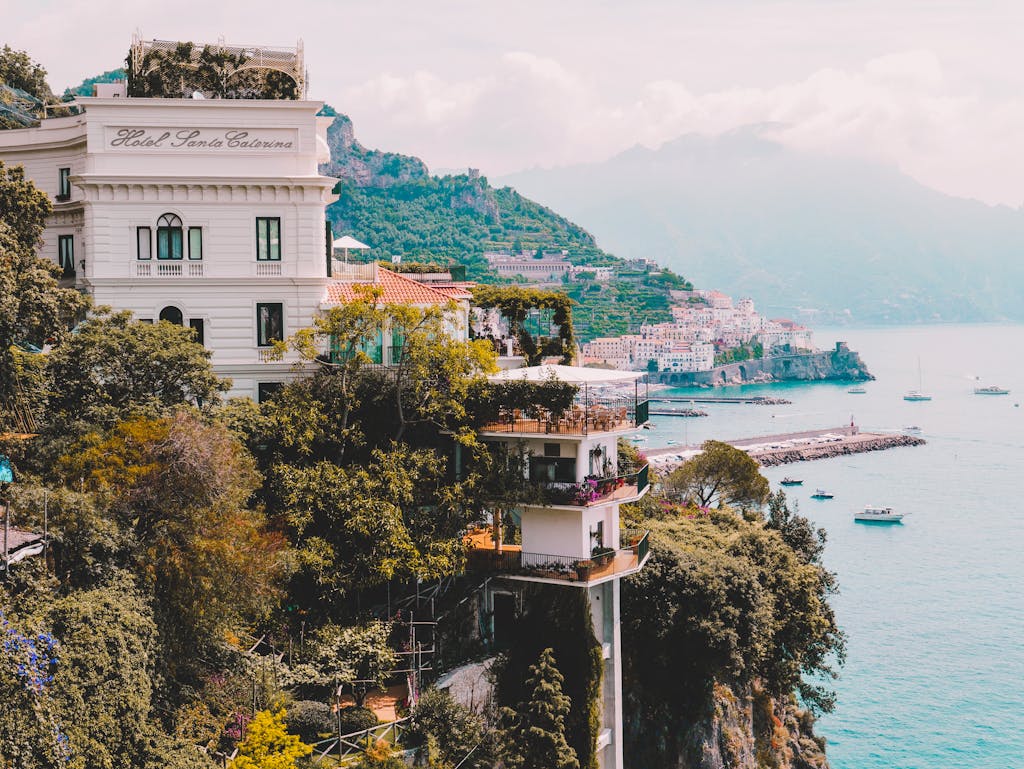 10 Rutas en Tren por Europa que Debes Hacer 6 Stunning view of Amalfi Coast with cliffs, buildings, and boats. Perfect for travel and architecture lovers.
