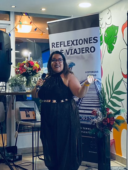 About Us - Traveleira & Brenda 3 Brenda being a speaker at event with floral decorations.