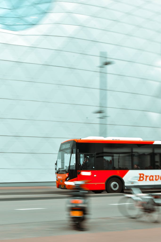 Resources 5 Dynamic cityscape with a red bus in motion, set against a modern building facade.